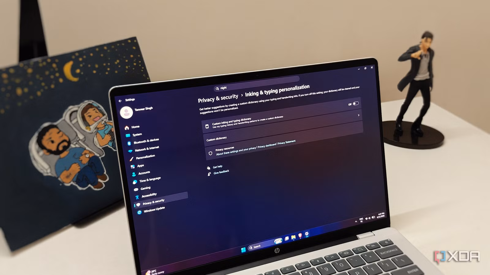 Ноутбук с Windows 11 на белом столе, демонстрирующий настройки конфиденциальности