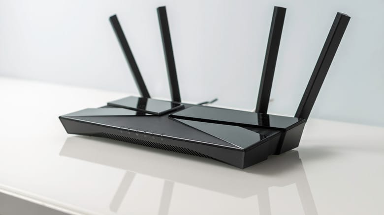Черный Wi-Fi роутер с внешними антеннами на белой поверхности
